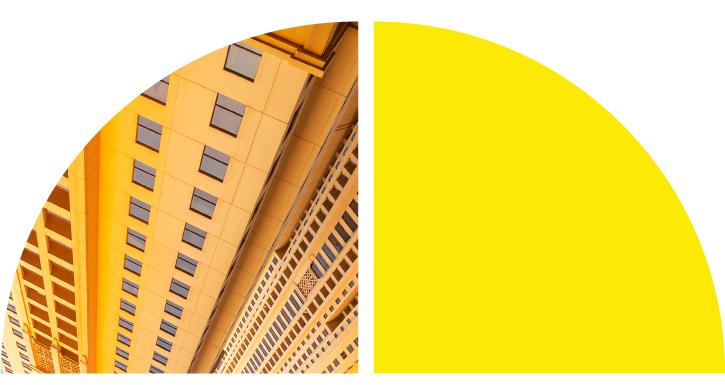 Modern building facade with diagonal lines in brown and yellow tones, next to a bright yellow semicircle on a split background.